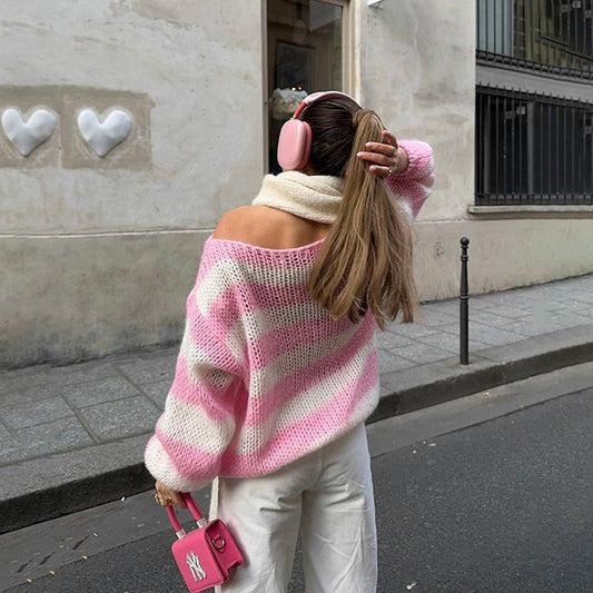 Woman wearing pink and white loose striped pullover sweater with off-shoulder design outdoors