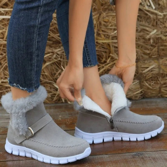 Women's gray winter snow boots with plush lining, suede upper, side zipper, buckle detail, and white rubber flat sole