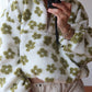 Women wearing white lambskin sweatshirt with green flower pattern and half zip-up collar in casual style