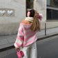 Woman wearing pink and white loose striped pullover sweater with off-shoulder design outdoors