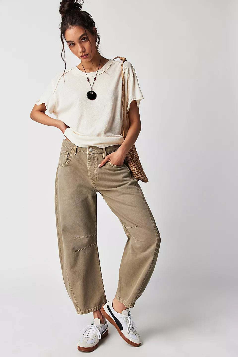 Women wearing casual high stretch mid-rise wide leg loose fit barrel jeans in dark khaki with white sneakers and off-white top