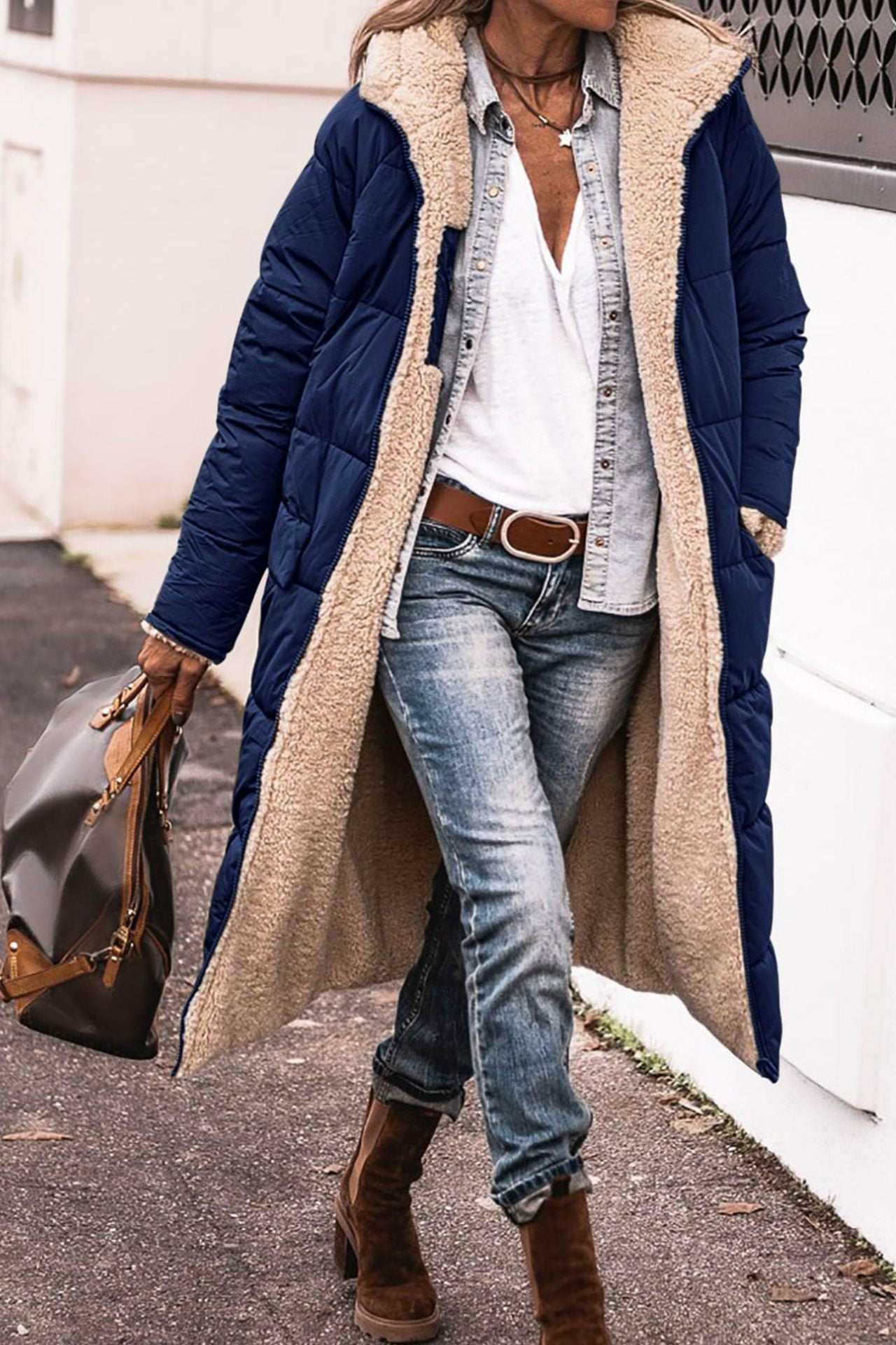 Solid color hooded long coat with soft beige lining and navy exterior, worn with casual jeans and boots.