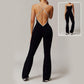 Woman wearing black Solid Beauty-back slim fit jumpsuit with crisscross open back, designed for yoga, fitness, and running.