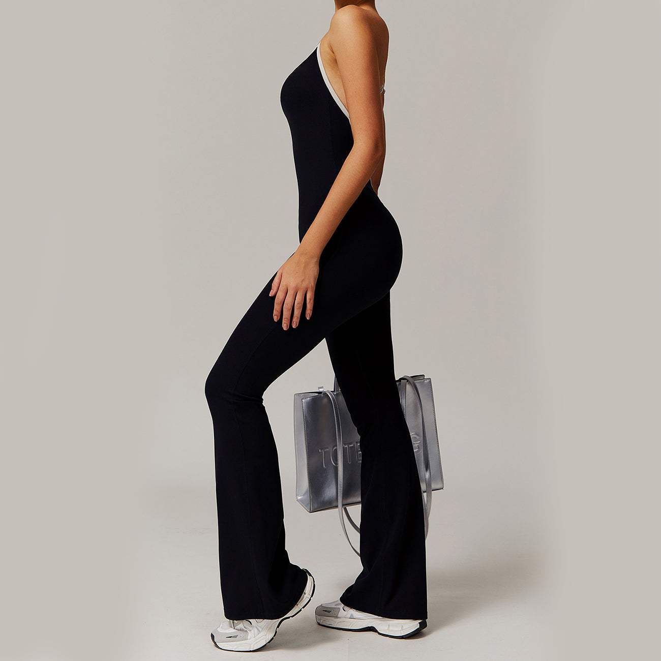 Woman wearing black Solid Beauty-back long pants jumpsuit with sneakers and transparent bag
