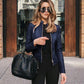 Woman wearing navy blue urban casual leather PU jacket with zipper and sunglasses carrying black handbag