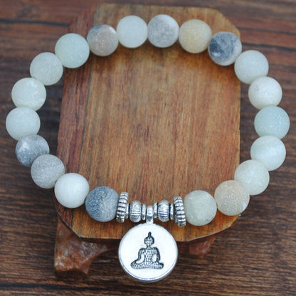 Handmade beaded frosted stone bracelet with Buddha charm on wooden background