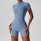 Woman wearing haze blue zipper short sleeve yoga jumpsuit with tight fit and moisture-wicking fabric