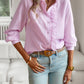 Women wearing pink striped long sleeve shirt with ruffle design and button-up front paired with light blue jeans
