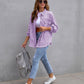 Woman wearing purple ripped shirt jacket with casual jeans and white sneakers carrying grey backpack outdoors