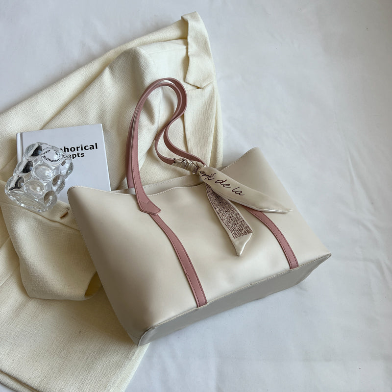 New and simple tote bag with large capacity and rose pink shoulder straps, styled with a beige scarf accessory.