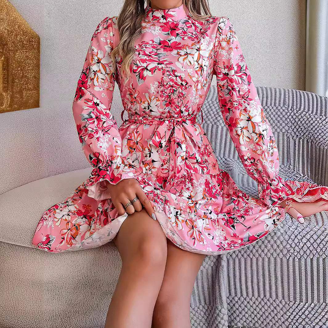 Woman wearing pink standing collar floral print long sleeve ruffled A-line dress sitting on a sofa