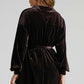 Back view of a woman wearing a dark purple velvet dress with loose waist and lapel collar, women's gold velvet dress style
