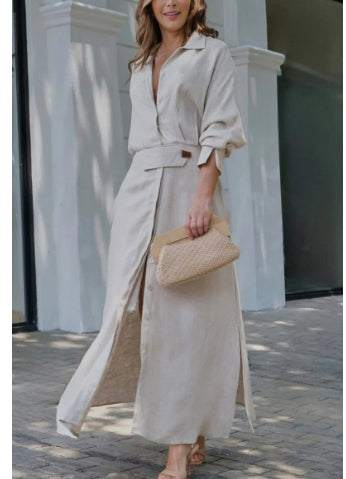 Woman wearing elegant tied solid color waisted long-sleeved shirt dress with slit and holding woven clutch.