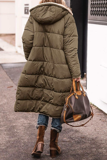 Woman wearing solid color hooded long winter coat with mid-length and raglan sleeves carrying brown handbag