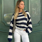 Woman wearing a navy and white loose striped pullover sweater with long sleeves and knitted texture