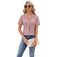 Woman wearing pink V-neck hollow design T-shirt with short sleeves and blue jeans while holding a white clutch bag