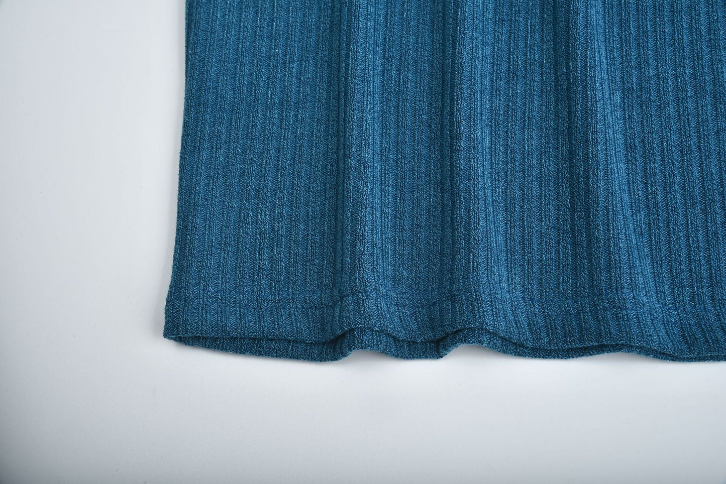 Close-up of blue cotton blend ribbed knit fabric on women's lapel pullover sweater hem