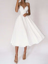 Woman wearing white sexy V-neck suspender A-line summer dress with thin straps and flowing skirt