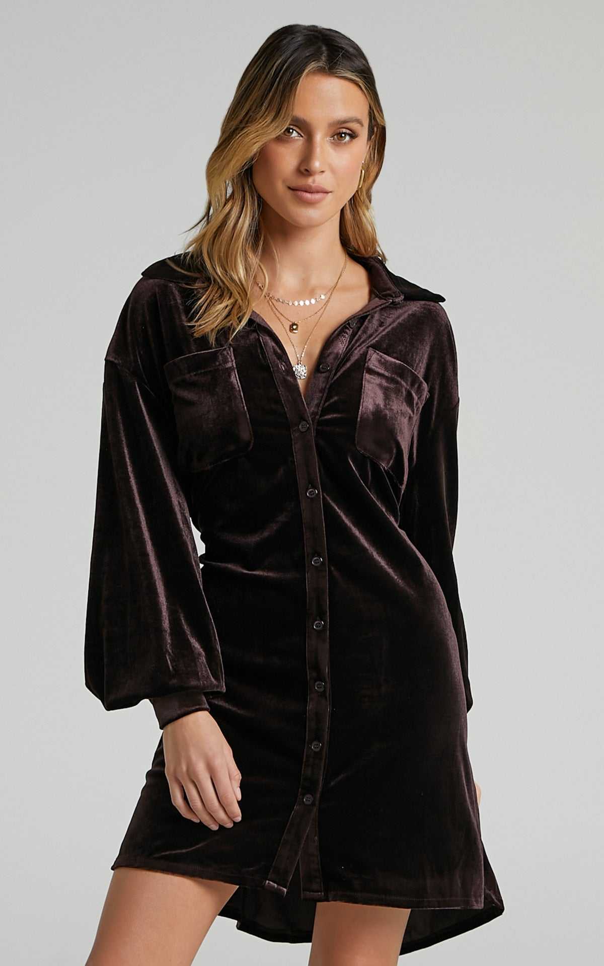 Woman wearing long sleeve dark brown velvet dress with lapel collar and button-down front