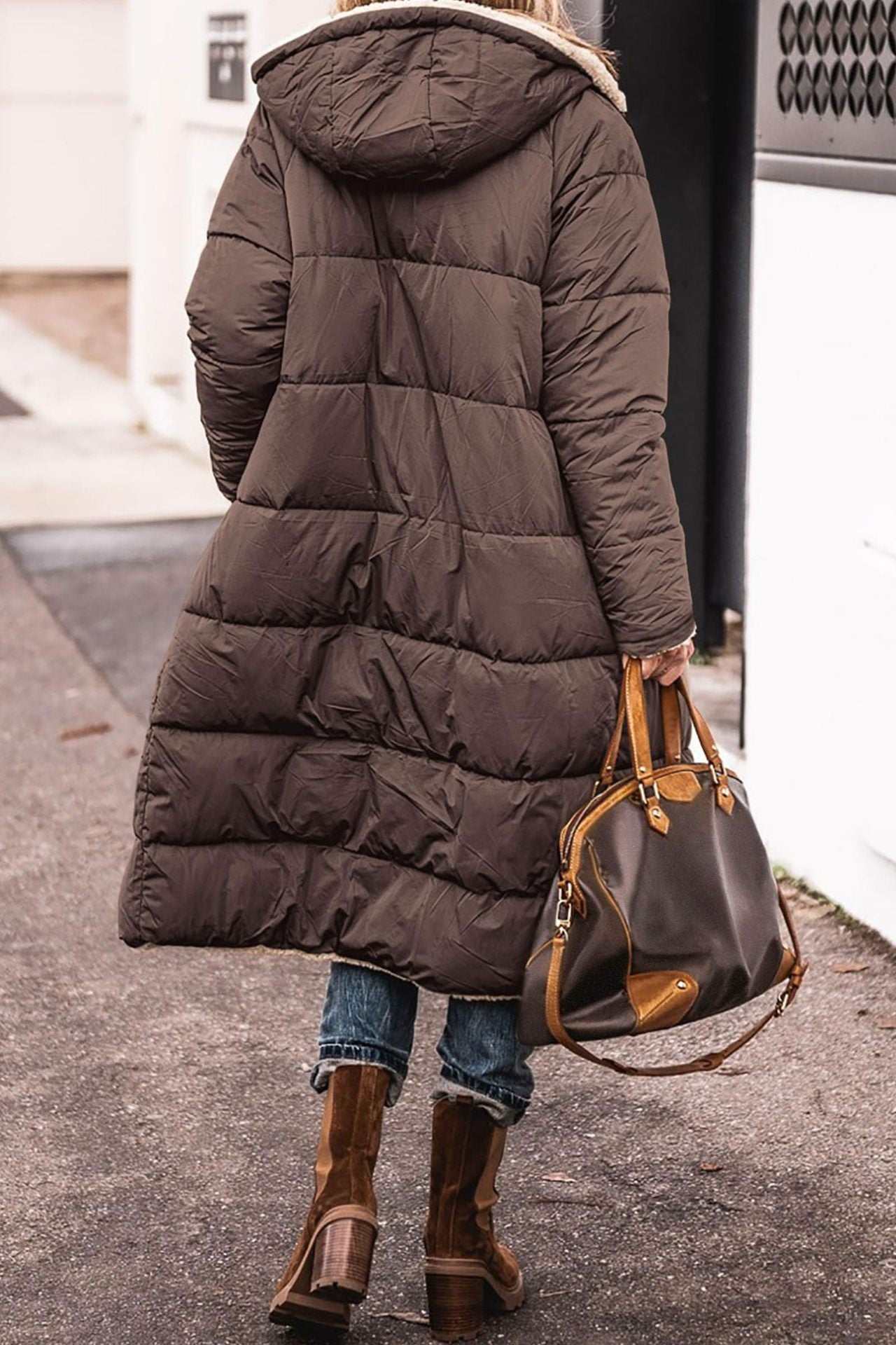 Woman wearing a solid color hooded long winter coat with long sleeves and mid-length design walking outdoors