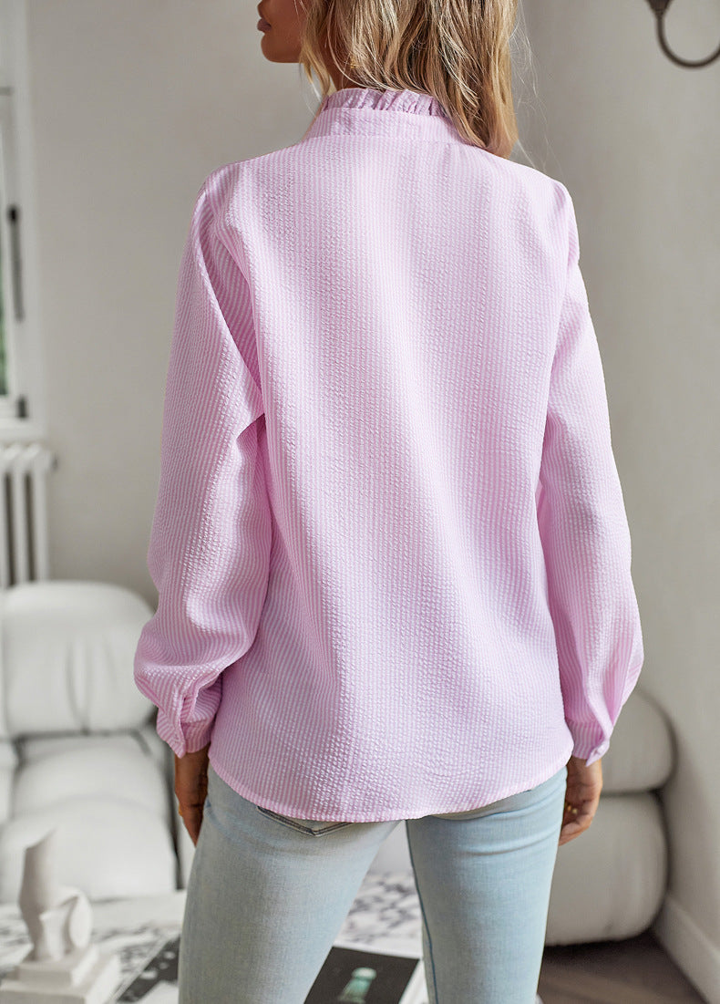 Back view of woman wearing pink striped long sleeve ruffle collar shirt with casual office style