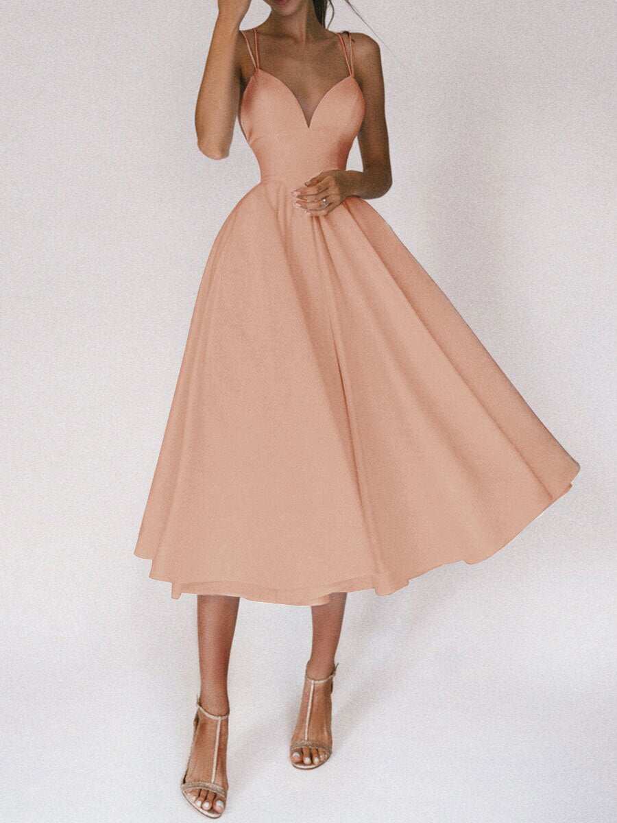 Woman wearing a peach sexy V-neck suspender A-line summer dress with spaghetti straps and high heels