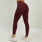 Woman wearing maroon high waist seamless scrunch butt yoga pants and white sneakers standing on white floor