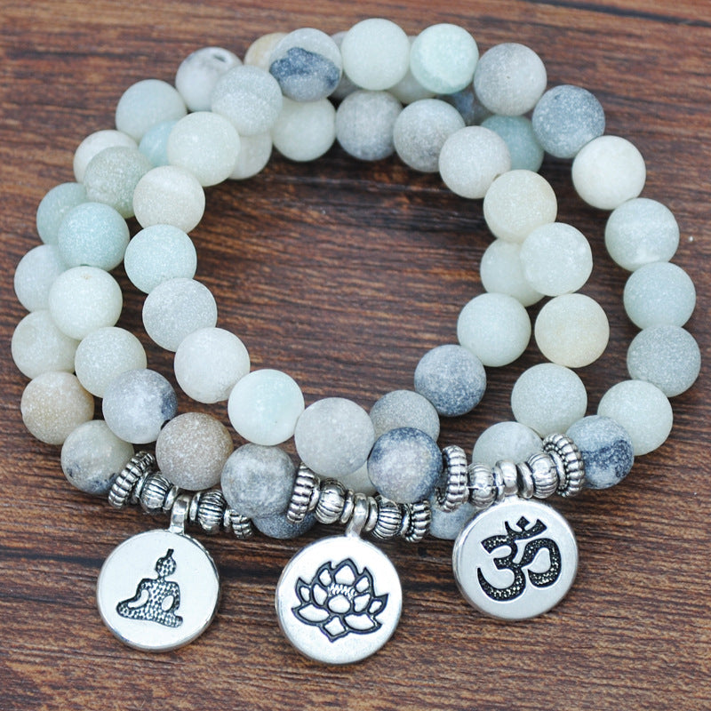 Handmade beaded frosted succulent yoga bracelet with stone beads and metal charms on wooden surface