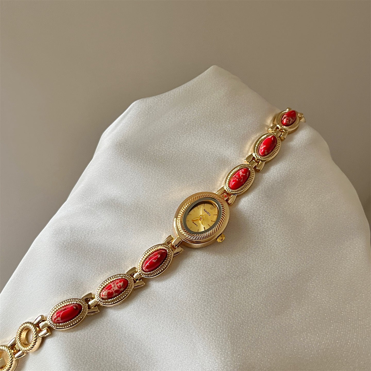 Women's agate bead bracelet watch with gold alloy and analog quartz movement on white fabric background