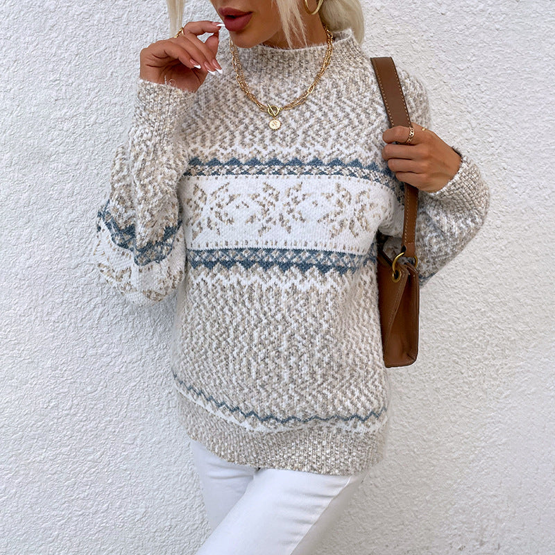 Woman wearing a cozy winter snowflake sweater with half turtleneck and jacquard knit design, styled casually with white pants and gold jewelry