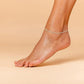 Delicate beach anklet with sparkling rhinestones on ankle against a neutral background