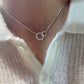 Women's fashionable minimalist silver interlocking ring clavicle necklace on a person wearing a cream knit sweater