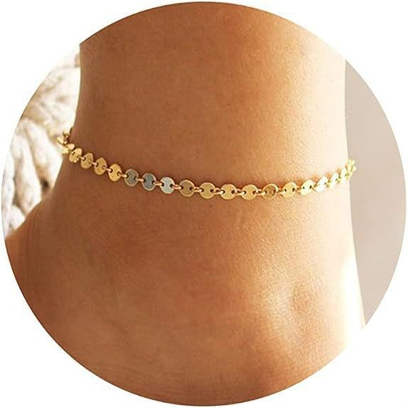 Gold round-disc beach anklet with star, heart, pearl, and bead accents on ankle