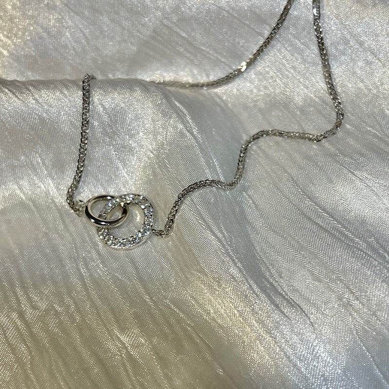 Women's fashionable minimalist silver interlocking ring clavicle necklace on satin background
