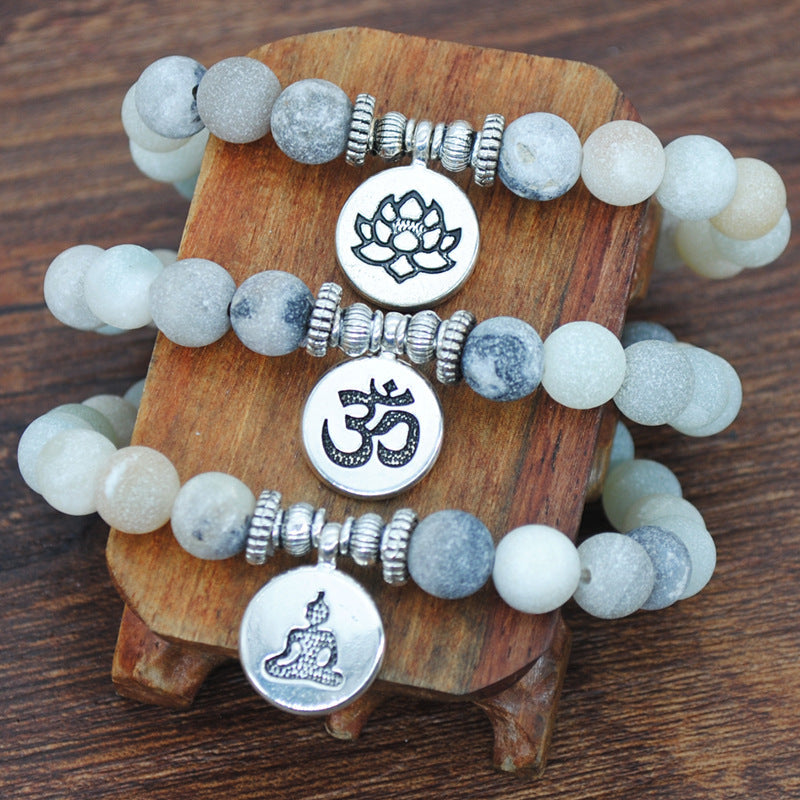 Handmade beaded frosted stone and alloy yoga bracelets with geometric silver charms on wooden display