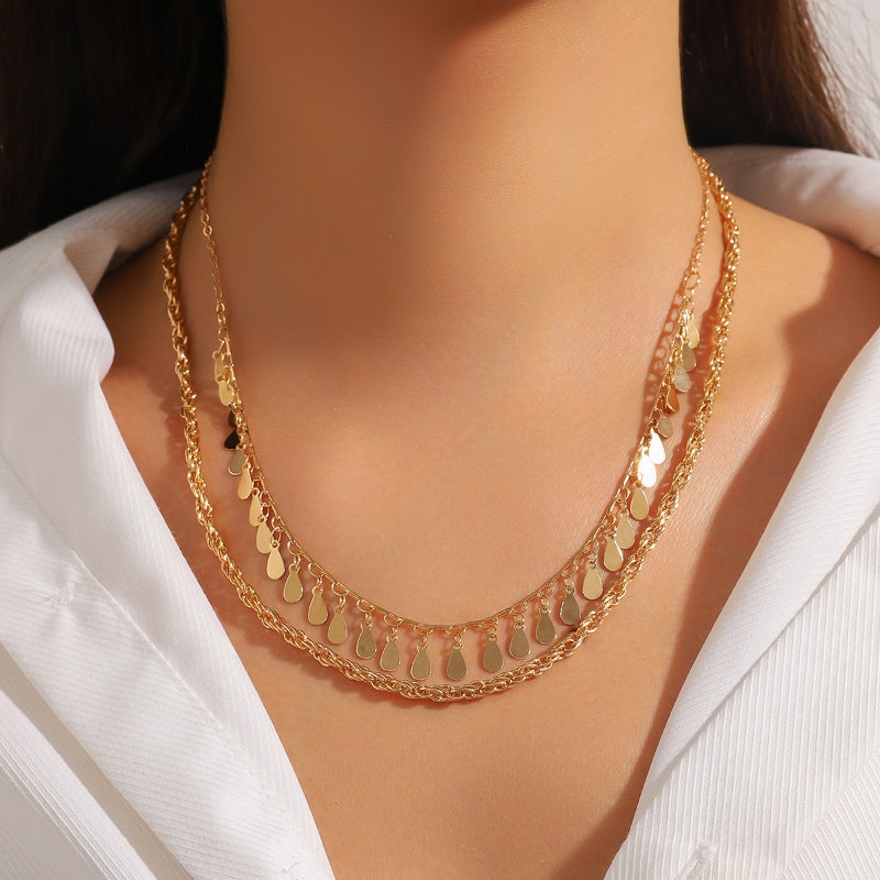 Gold multi-layer braided chain necklace with disc droplets and waterdrop-shaped tassels on a woman's neck