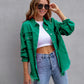 Female model wearing green ripped shirt jacket with frayed edges, white crop top, and blue jeans