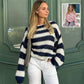 Woman wearing loose striped pullover sweater with navy and white stripes paired with white pants
