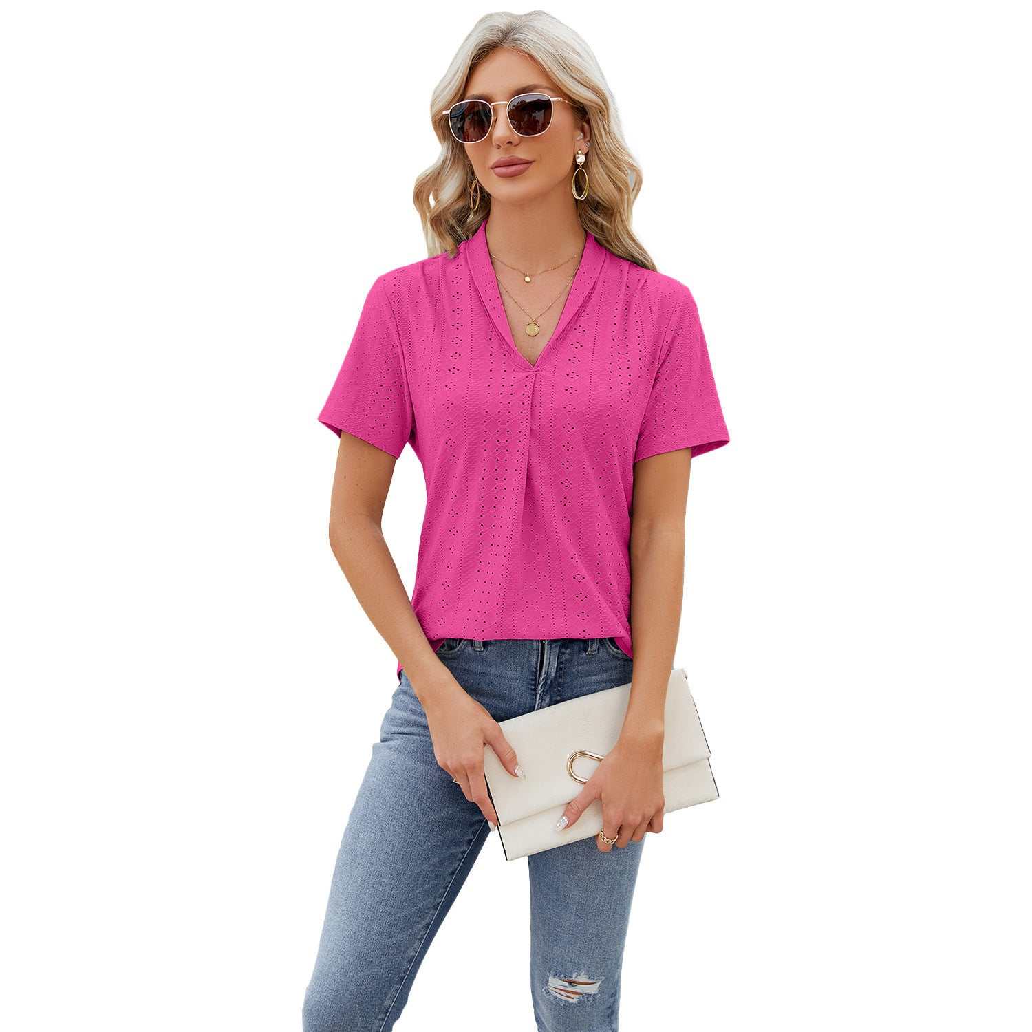 Woman wearing pink V-neck hollow design summer loose short-sleeved T-shirt with sunglasses and jeans holding a white clutch bag