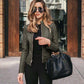 Woman wearing an urban casual leather PU suit jacket in army green with zipper and stitching details, holding a black handbag.